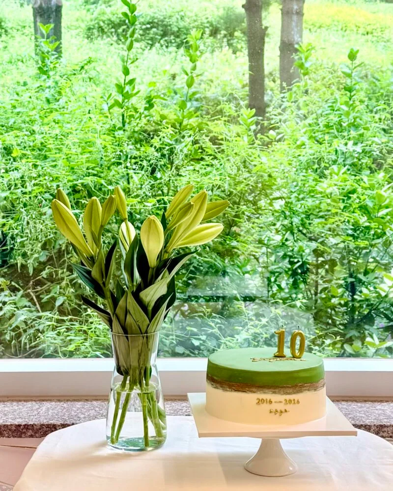 숲이 보이는 창가의 요가트리 10주년 케이크와 꽃